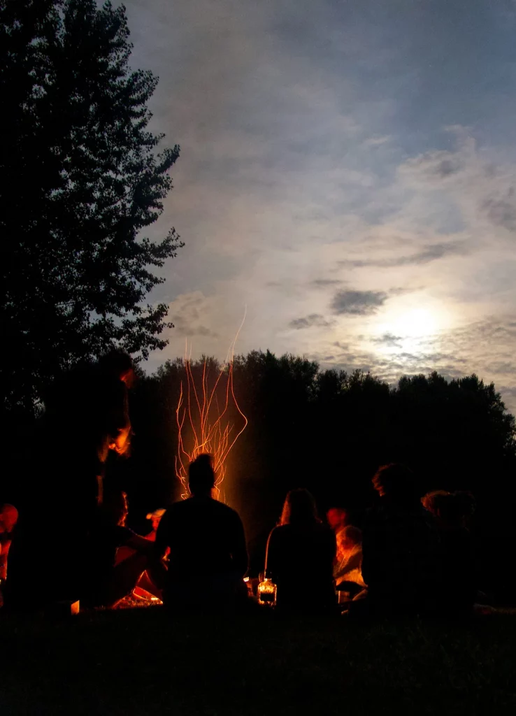 Freunde sitzen um ein Feuer in der Wildnis, nachts bei Mondschein